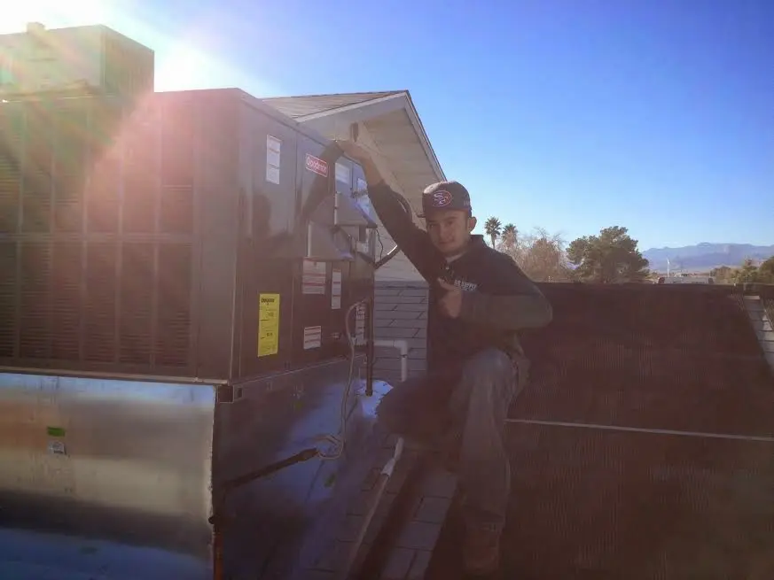 HVAC technician performing AC Tune-Up on a rooftop unit in Durant